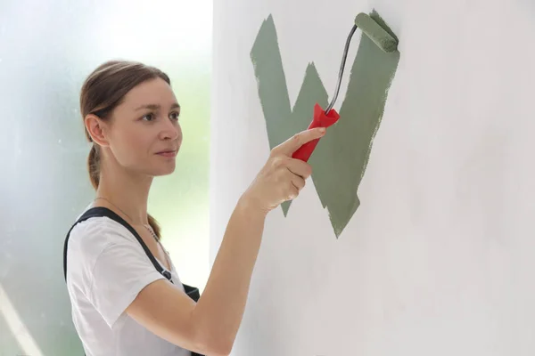 在白色墙壁上涂上绿色油漆的妇女 — 图库照片