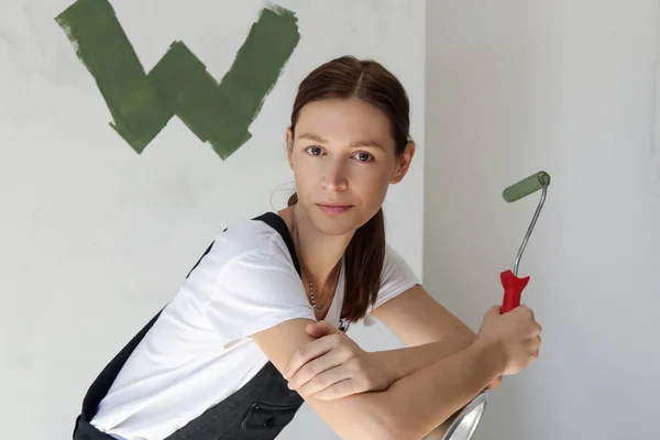 ペイントローラーを持ち はしごに寄りかかって リノベーションDiyコンセプトで休憩を取る若い女性の肖像画 — ストック写真