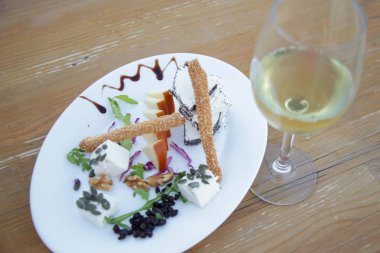 Basit bir şekilde seçilmiş peynir tabağı zanaatkar peyniri meyve ve bir bardak beyaz şarapla fındık.