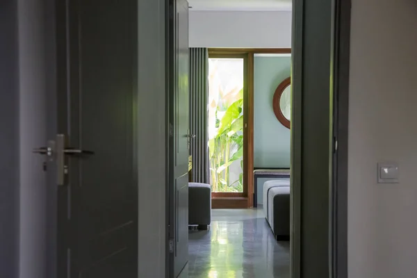 A view through the door to the bedroom in a modern simple green toned home