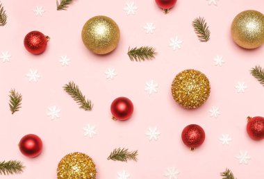 Altın ve kırmızı Noel topları ve soluk pembe arka planda köknar dalları. Noel süsü aranjmanı.