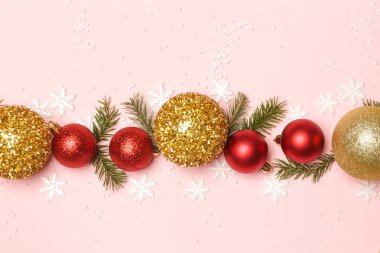 Altın ve kırmızı Noel topları ve soluk pembe arka planda köknar dalları. Noel süsü aranjmanı.