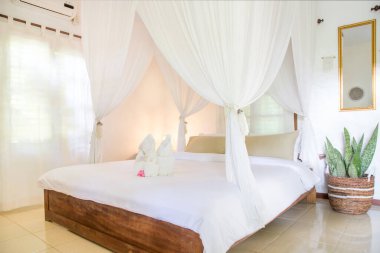 Büyük boy yatak, sivrisinek ağlı, yatak odasının içi beyaz renklerde, insan yok.