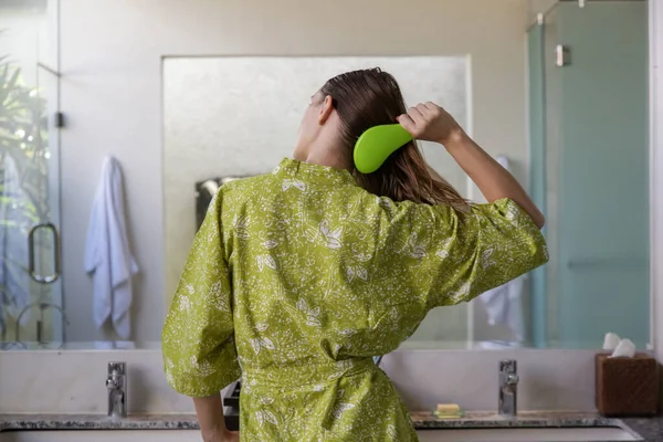 ヘアケア 鏡の前のバスルームでプラスチック製のデタングリング髪ブラシと髪をもたらすブルネットの女性のまれなビュー — ストック写真