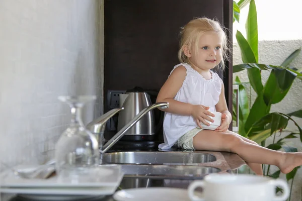 Niña Sentada Mostrador Cocina Sosteniendo Una Taza Con Agua Imagen — Foto de Stock