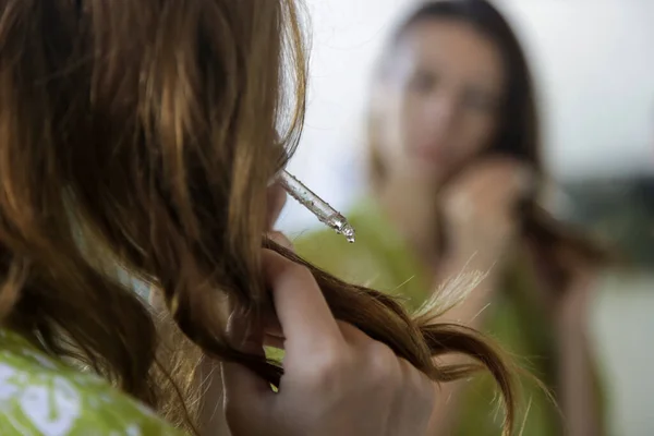 ヘアケア 鏡の前の浴室では 髪にオイルを塗る女性が終わります 髪の先端 乾燥した髪や太陽の保護の概念を分割 — ストック写真