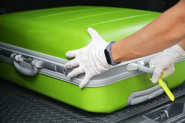 Safety measures during coronavirus, hotel employee  wearing protective rubber gloves to take suitcase from car trunk before disinfection.