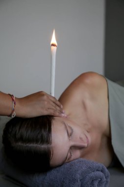 Spa 'da kulak mumu tedavisi gören bir kadın. Kulak konisi ya da termal auriküler terapi.
