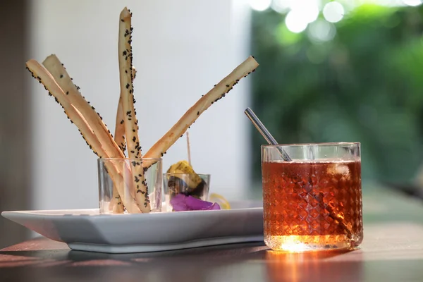 Salty sticks and iced tea served on the restaurant table.