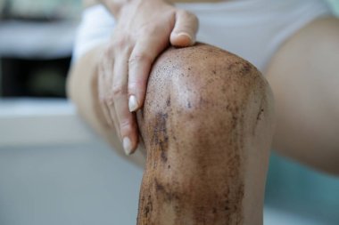 Kahve fırçası. Güzel cilt bakımı. Genç bir kadın bacaklarına kahve fırçası sürüyor..