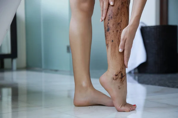 DIY Coffee scrub. Beauty skin care. Young woman putting coffee scrub on her legs.