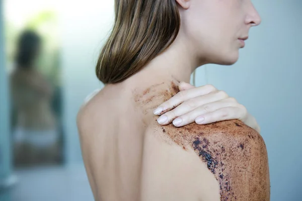 DIY Coffee scrub. Beauty skin care. Young woman putting coffee scrub on her neck and shoulders.