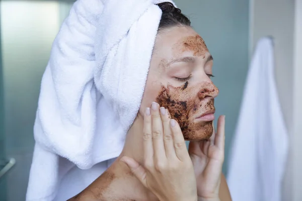 DIY Coffee scrub face mask. Beauty skin care. Portrait of young woman with coffee scrub on her face.