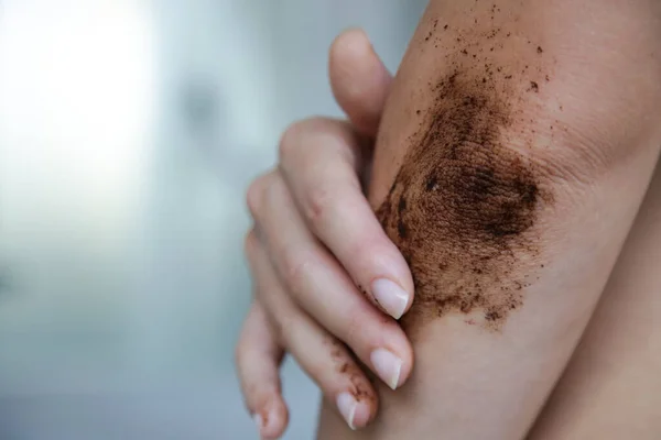 DIY Coffee scrub. Beauty skin care. Young woman putting coffee scrub on dry elbow skin.