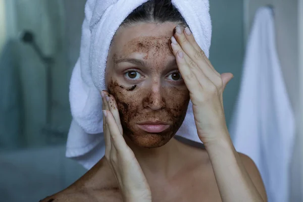 DIY Coffee scrub face mask. Beauty skin care. Portrait of young woman with coffee scrub on her face.