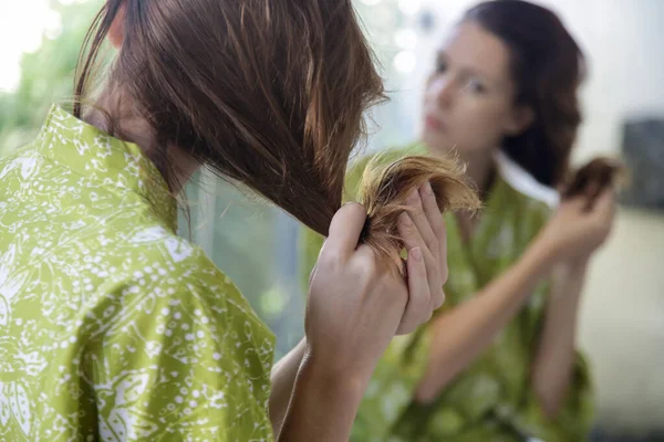 女人看着她干枯纠结的头发 — 图库照片