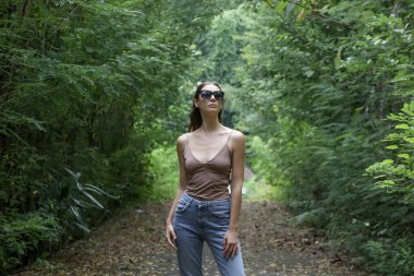 Gecelik gömlek ve kot pantolon giymiş, ormanın temiz havasının tadını çıkaran Kafkas bir kadının portresi. Barış ve uyum kavramı. 