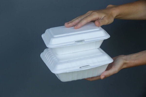 Woman's hands holding takeaway foam lunch boxes. Single use food containers, close up.