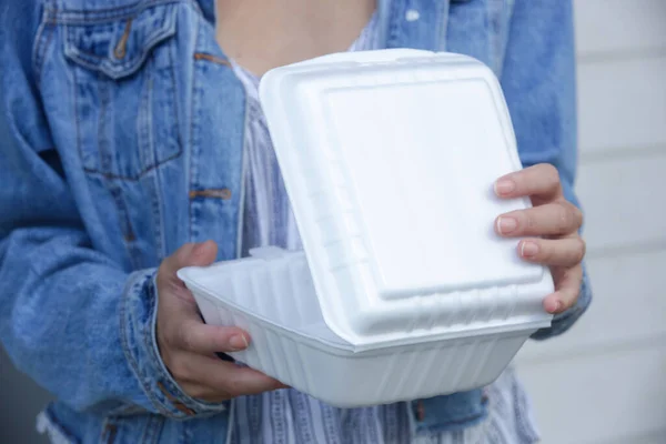 Woman\'s hands holding takeaway foam lunch boxes. Single use food containers, close up.