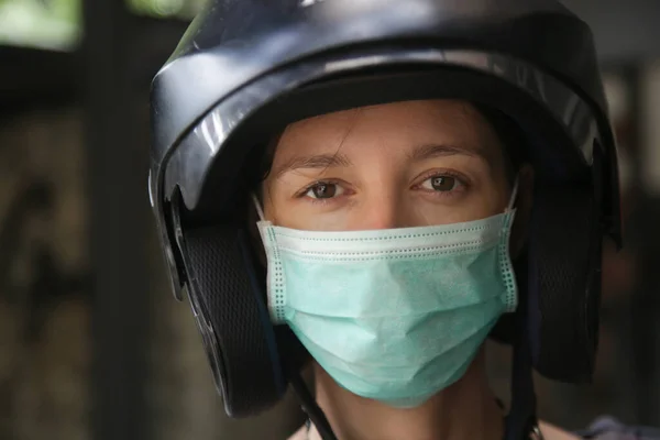 Close up portrait of caucasian woman wearing helmet and medical protective mask, looking at camera