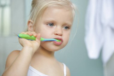 3 yaşında bir kız banyoda dişlerini fırçalıyor..