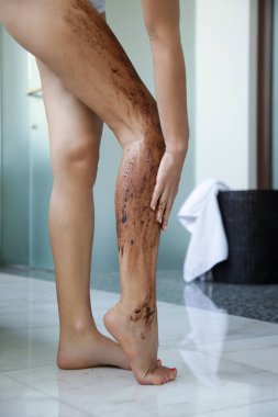 Kahve fırçası. Güzel cilt bakımı. Genç bir kadın bacaklarına kahve fırçası sürüyor..