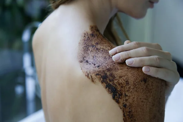 DIY Coffee scrub. Beauty skin care. Young woman putting coffee scrub on her neck and shoulders.