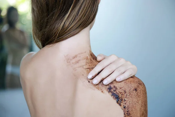 DIY Coffee scrub. Beauty skin care. Young woman putting coffee scrub on her neck and shoulders.