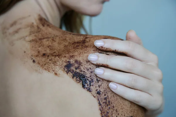 DIY Coffee scrub. Beauty skin care. Young woman putting coffee scrub on her neck and shoulders.