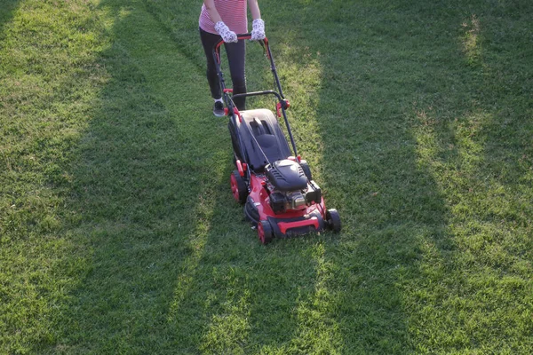 芝生の芝刈り機で草を切る若い女性 屋外家事コンセプト — ストック写真
