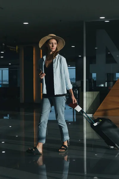 Τουριστική Γυναίκα Καπέλο Και Χειραποσκευή Περιμένει Την Πτήση Στο Αεροδρόμιο — Φωτογραφία Αρχείου