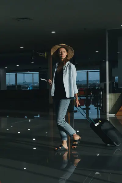 Τουριστική Γυναίκα Καπέλο Και Χειραποσκευή Περιμένει Την Πτήση Στο Αεροδρόμιο — Φωτογραφία Αρχείου