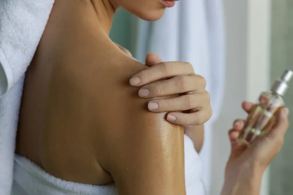 Duştan sonra cildini nemlendirmek için vücut yağı süren bir kadın. Güzellik bakımı konsepti.