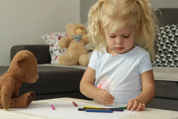Adorable blonde toddler girl drawing with crayons. Drawing can enhance children\'s motor skills from a young age and will help them improve their hand and eye coordination.