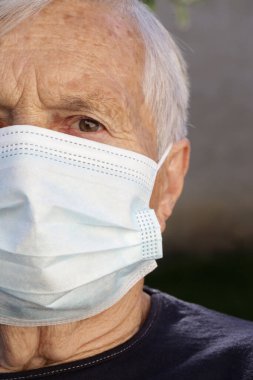 Koruyucu tıbbi maske takan yaşlı beyaz kadın portresi. Koronavirüs salgını sırasında güvenlik önlemleri.