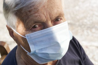 Koruyucu tıbbi maske takan yaşlı beyaz kadın portresi. Koronavirüs salgını sırasında güvenlik önlemleri.