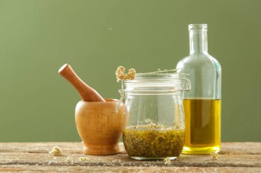 Bitkisel içerikli yağ. Sarı immortelle çiçekleri, soğuk sıkılmış zeytinyağı, harç ve tokmak. Yenileme süreci.