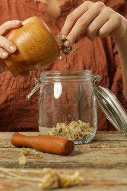 Sarı çiçekli bitkisel yağ üreten bir kadın. Doğal organik kozmetik için macerlaşma süreci.