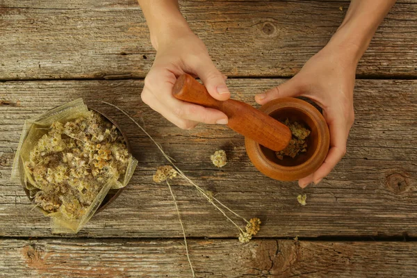 Woman preparing natural medicines with mortar and pestle. Process of making natural cosmetic or herbal infused oil.