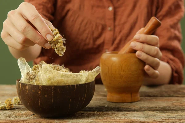 Woman preparing natural medicines with mortar and pestle. Process of making natural cosmetic or herbal infused oil.