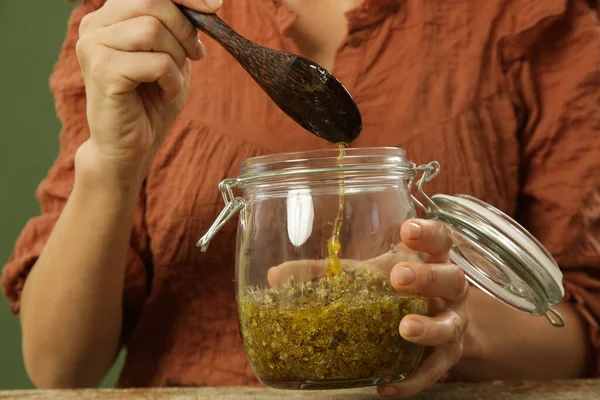 Sarı çiçekli bitkisel yağ üreten bir kadın. Doğal organik kozmetik için macerlaşma süreci.