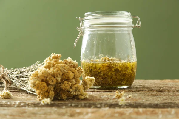 Bitkisel yağ. Sarı immortelle çiçekleri ve cam kavanozda soğuk sıkılmış zeytinyağı. Yenileme süreci.