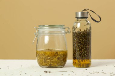 Sarı immortelle ve lavandula çiçekleriyle bezenmiş bitkisel yağlar. Yenileme süreci.