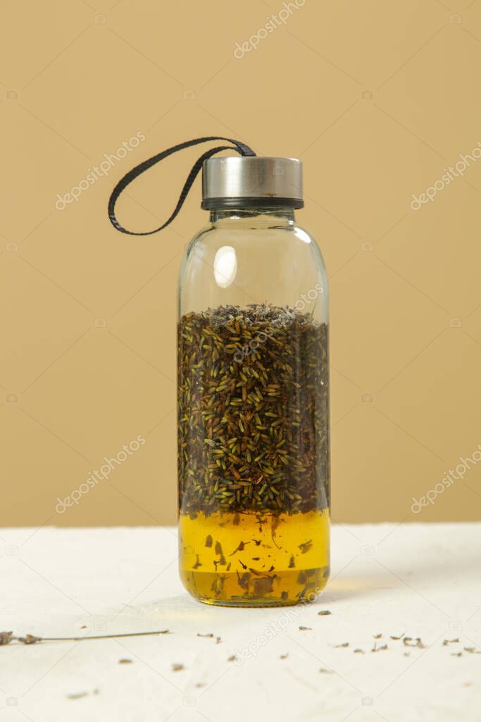 Herbal infused oil with lavandula flowers in a glass bottle. Process of maceration.