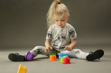 Gri arka planda 3 yaşındaki modaya uygun çocuğun stüdyo çekimi.