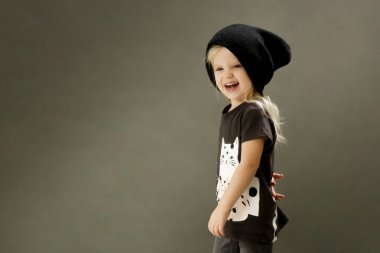 Gri arka planda 3 yaşındaki modaya uygun çocuğun stüdyo çekimi.