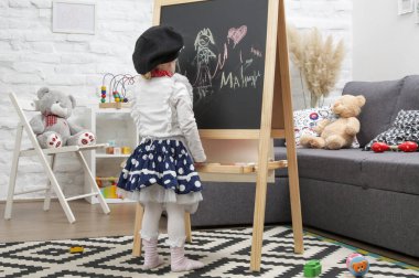 Ressam gibi giyinmiş 3 yaşındaki sevimli kızın kapalı mekândaki portresi.