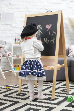 Ressam gibi giyinmiş 3 yaşındaki sevimli kızın kapalı mekândaki portresi.