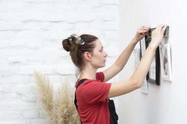 Yeni evin duvarlarında resim çerçeveleri düzenleyen kadın, ev geliştirme konseptini bozuyor.