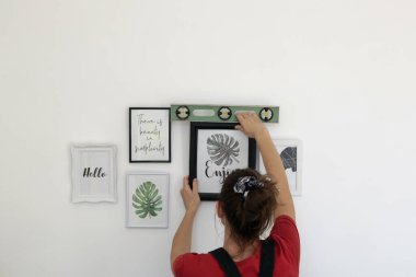 Yeni evin duvarlarında resim çerçeveleri düzenleyen kadın, ev geliştirme konseptini bozuyor.